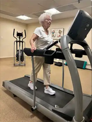 Isabel, a 95-year-old Vintage Fitness client, smiling and standing confidently, celebrating her active lifestyle and progress with her personal trainer, Aarti.